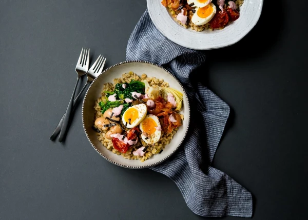 Healthy and delicious meal in a bowl: barley lentil mixed grains with all the fixing of spinach, roasted tomatoes, artichoke hearts, giant white beans, kimchi and an egg on top.  A horseradish beet Tahini cream goes nicely with it.